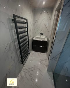 Bathroom with marble-effect tiles, a black towel radiator and vanity basin